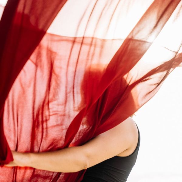Woman in a dynamic yoga flow pose, surrounded by a soft light.